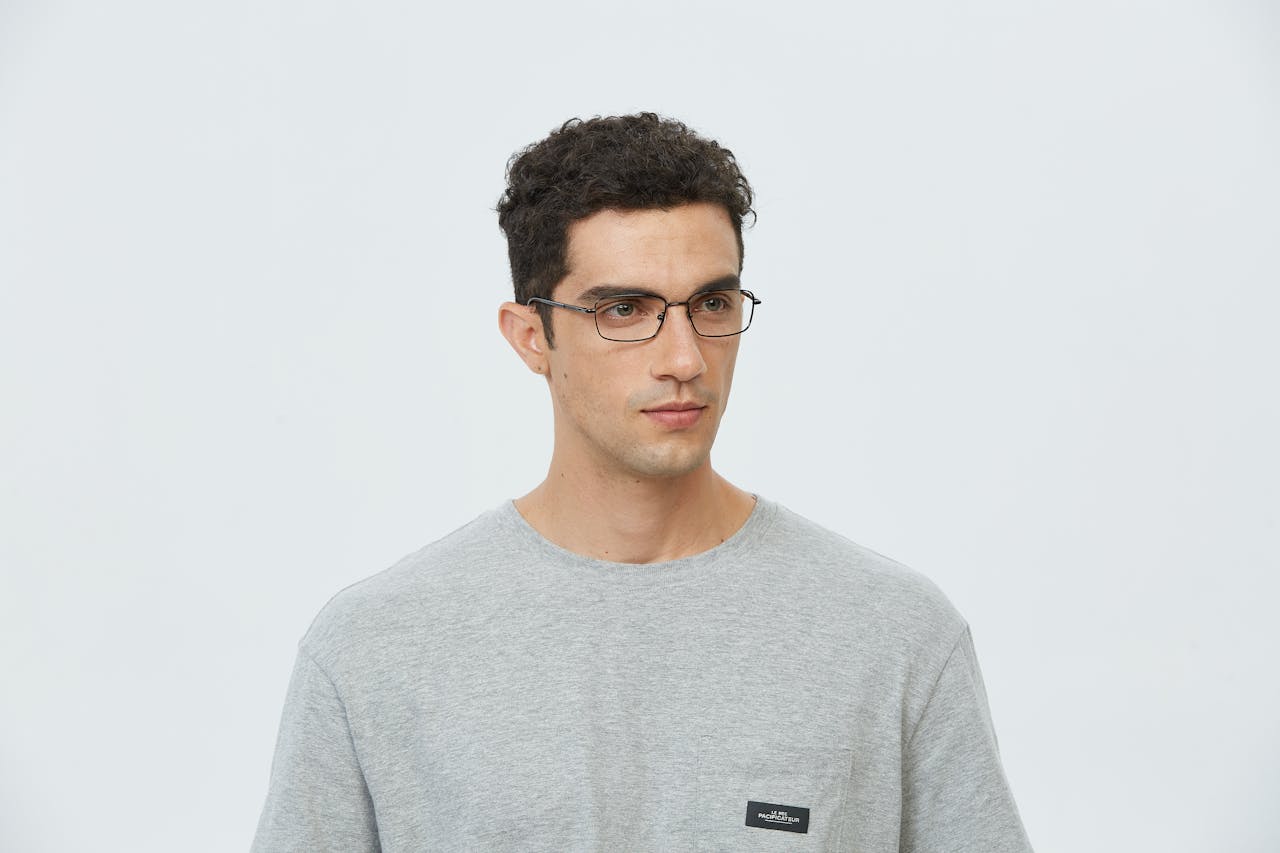 Portrait of a young man wearing glasses and a gray T-shirt in a studio setting.